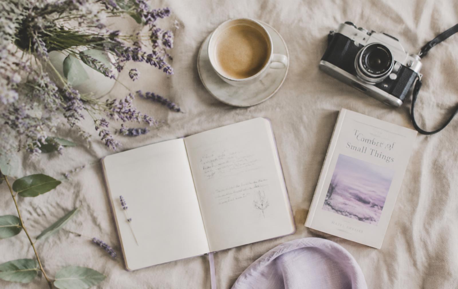 Linen flat lay with notebook, coffee, lavender and camera